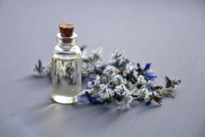 lavander essential oil small bottle next to a lavander branch